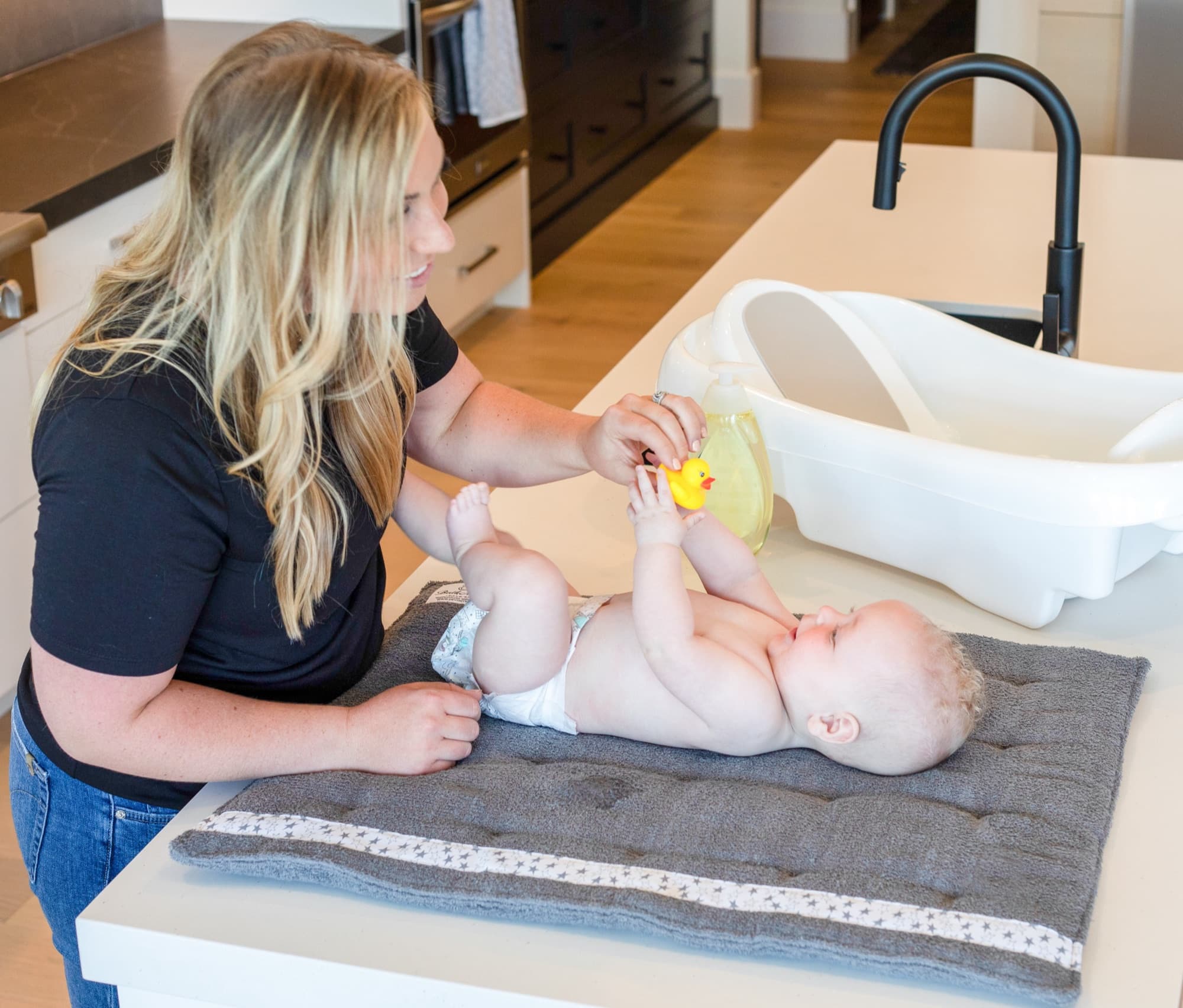 A mother drying her baby on a BathMatty laid across the kitchen counter